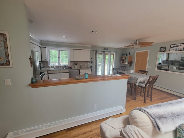 A modern kitchen with a central island, a dining area with a table and chairs, and a ceiling fan.