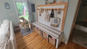 A cozy living room with a wooden bench, a dog, and a door leading outside. - Beautiful private home with beach access down the block (Southold)