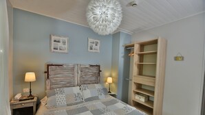 Ein Schlafzimmer mit einem Bett, zwei Nachttischen, einem Schminktisch, einem Holzschrank und einer Deckenleuchte.