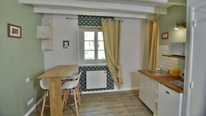 Eine kleine Küche mit Holztisch und -stühlen, einem Spülbecken und einem Kühlschrank.