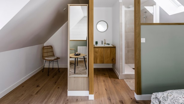Ein modernes Lofts Schlafzimmer mit Dachfenster, Holzboden, einer kleinen Essecke und einem Badezimmer mit Dusche.