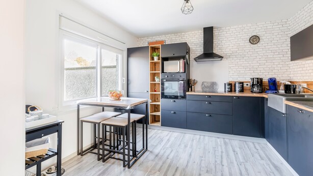 Une cuisine moderne dotée d’un îlot central, d’appareils électroménagers intégrés et d’un mur décoratif en briques.