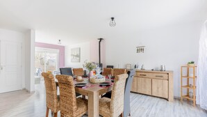 Un coin repas avec une table en bois et des chaises en osier, un buffet en bois et une porte blanche.