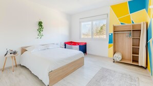 Une chambre moderne avec un lit, une petite table sur laquelle est posé un vélo, une armoire et une fenêtre donnant sur un beau paysage.