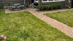 Une maison à deux étages avec un patio couvert, une cheminée et un petit jardin.