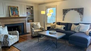 Un salon avec une cheminée, un canapé, un fauteuil et une table basse.