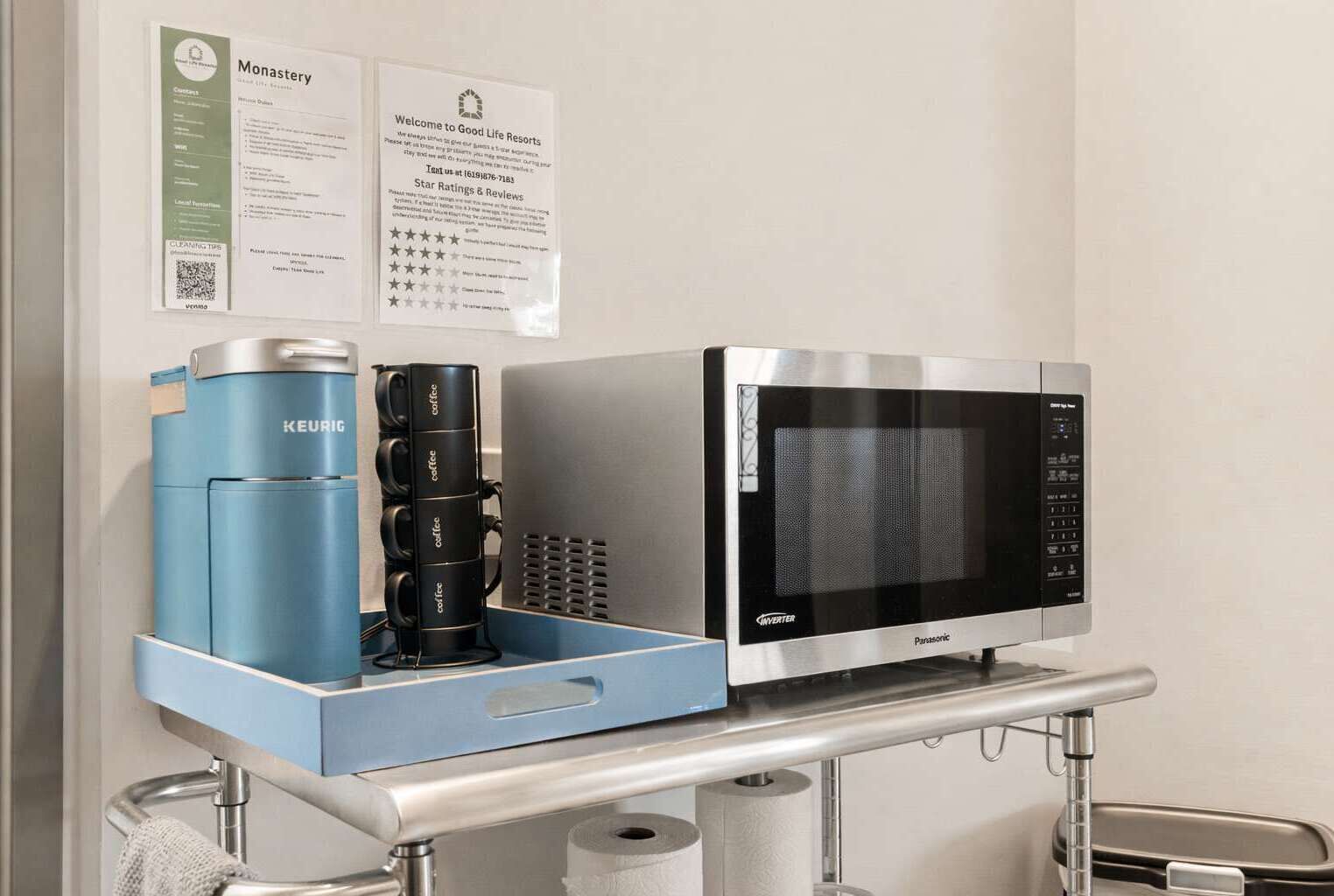 Een kitchenette met een Keurig koffiezetapparaat, een Panasonic magnetron en een bord met informatie over Good Life Resorts.