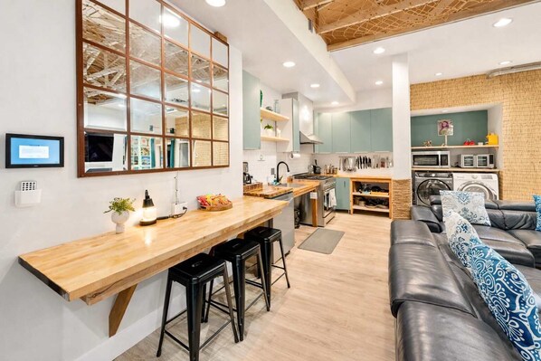 A modern kitchen with a wooden countertop, bar stools, and a built-in oven.