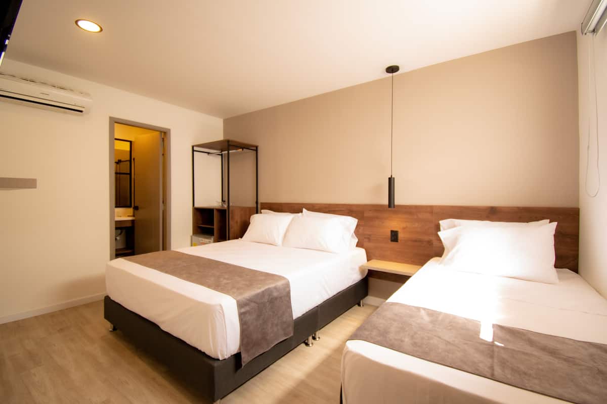 A modern hotel room with two beds, a wooden headboard, a bedside table, and a large mirror.