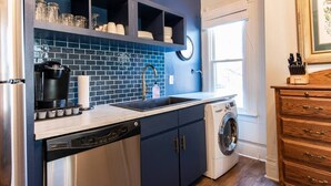 A compact kitchen with a dishwasher, washing machine, and a sink. - The Gallery Loft - Walk & Dine! (Louisville)