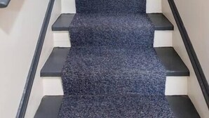 A staircase with a grey carpet and white steps, leading to a framed picture on the wall. - The Gallery Loft - Walk & Dine! (Louisville)