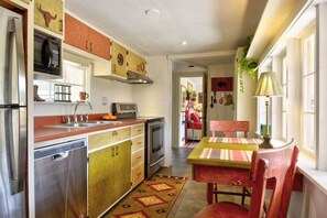 A compact kitchen with a refrigerator, microwave, stove, and sink. There's a dining area with a table and chairs. - Pub -  Hot Tub - Fire Pit (Green Mountain Falls)