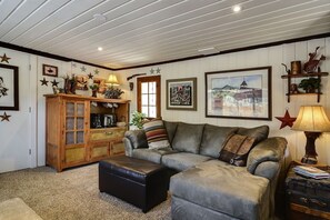 Ein gemütliches Wohnzimmer mit einem Ledersofa, einem Holzschrank und einem gerahmten Bild an der Wand.