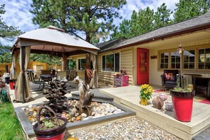 A log cabin with a covered patio, outdoor seating, and a decorative water feature.