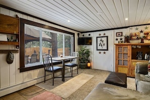 A cozy room with a dining table, chairs, a TV, and a fireplace. - Pub -  Hot Tub - Fire Pit (Green Mountain Falls)