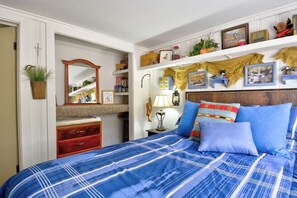 A bedroom with a bed, a dresser, a mirror, shelves with decorative items, and a wall-mounted plant. - Pub -  Hot Tub - Fire Pit (Green Mountain Falls)