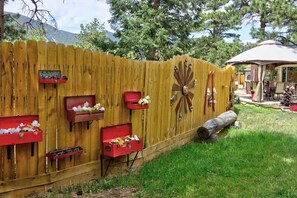 A wooden fence with red flower boxes and a decorative metal piece. - Pub -  Hot Tub - Fire Pit (Green Mountain Falls)