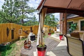 Eine Holzterrasse mit Grill, Holzzaun und Blumentöpfen.