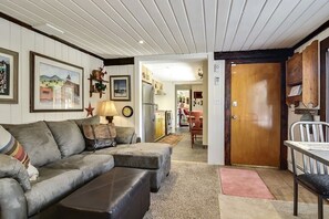 A cozy living room with a sofa, ottoman, and a dining area with a table and chairs.
