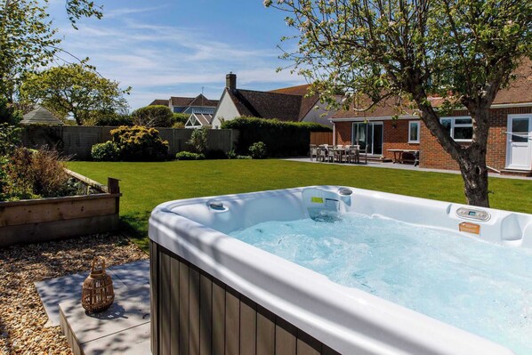 Ein Whirlpool in einem Garten mit Rasen, einem Ziegelhaus und einem Baum.