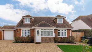 A two-story house with a brick facade, white-framed windows, and a front door. - Coastal Retreat for 8 with Hot Tub - Walk to Beach (Chichester)