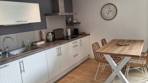 A modern kitchen with white cabinets, a wooden countertop, a stainless steel range hood, a coffee maker, and a clock on the wall. - Milady, Arcangues vacation rentals (Arcangues)