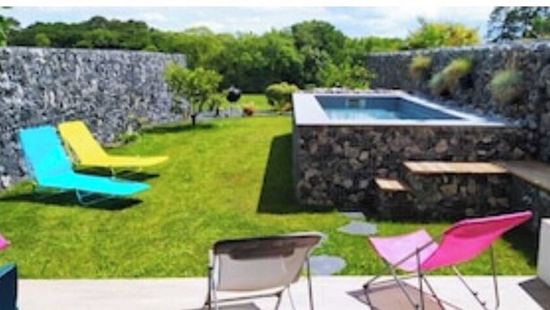 A backyard with a stone wall, a hot tub, and colorful lounge chairs. - Milady, Arcangues vacation rentals (Arcangues)