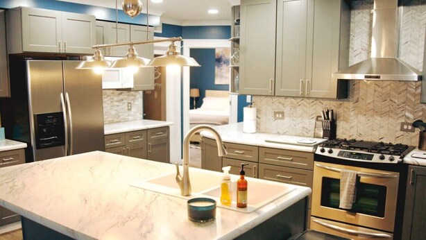 A modern kitchen with a large island, stainless steel appliances, and a herringbone tile backsplash. - Upscale luxury home just a few blocks from beach (Ludington)