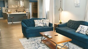 A modern living room with a blue sofa set, a wooden coffee table, and a patterned rug. - Upscale luxury home just a few blocks from beach (Ludington)