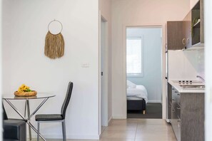 Une cuisine compacte avec un coin repas, un lit à l’arrière-plan et un élément décoratif fixé au mur.