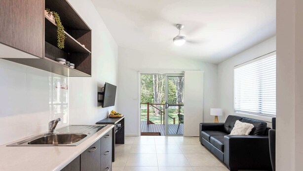 A modern kitchen with a built-in sink, dark cabinetry, and a flat-screen TV.