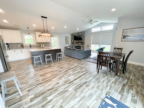 A spacious kitchen with a central island, bar stools, and a dining area with a table and chairs.