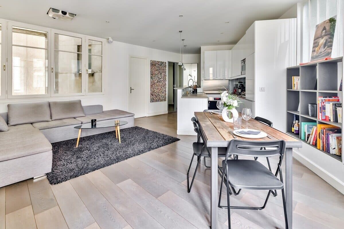 Una sala moderna con un sofá, una mesa de centro y un comedor con sillas y una mesa de madera.