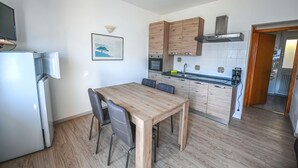 Ett kompakt kök med träskåp, en inbyggd ugn och en matplats med bord och stolar.