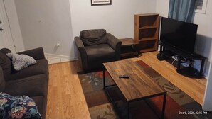A living room with a sofa, a coffee table, a TV, and a bookshelf.