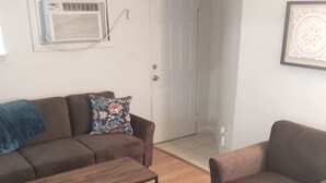 A living room with a brown sofa, a wooden coffee table, and a striped rug.