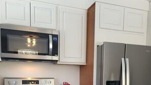 Eine Küche mit einem Edelstahl-Kühlschrank, einer Mikrowelle und einem Backofen.