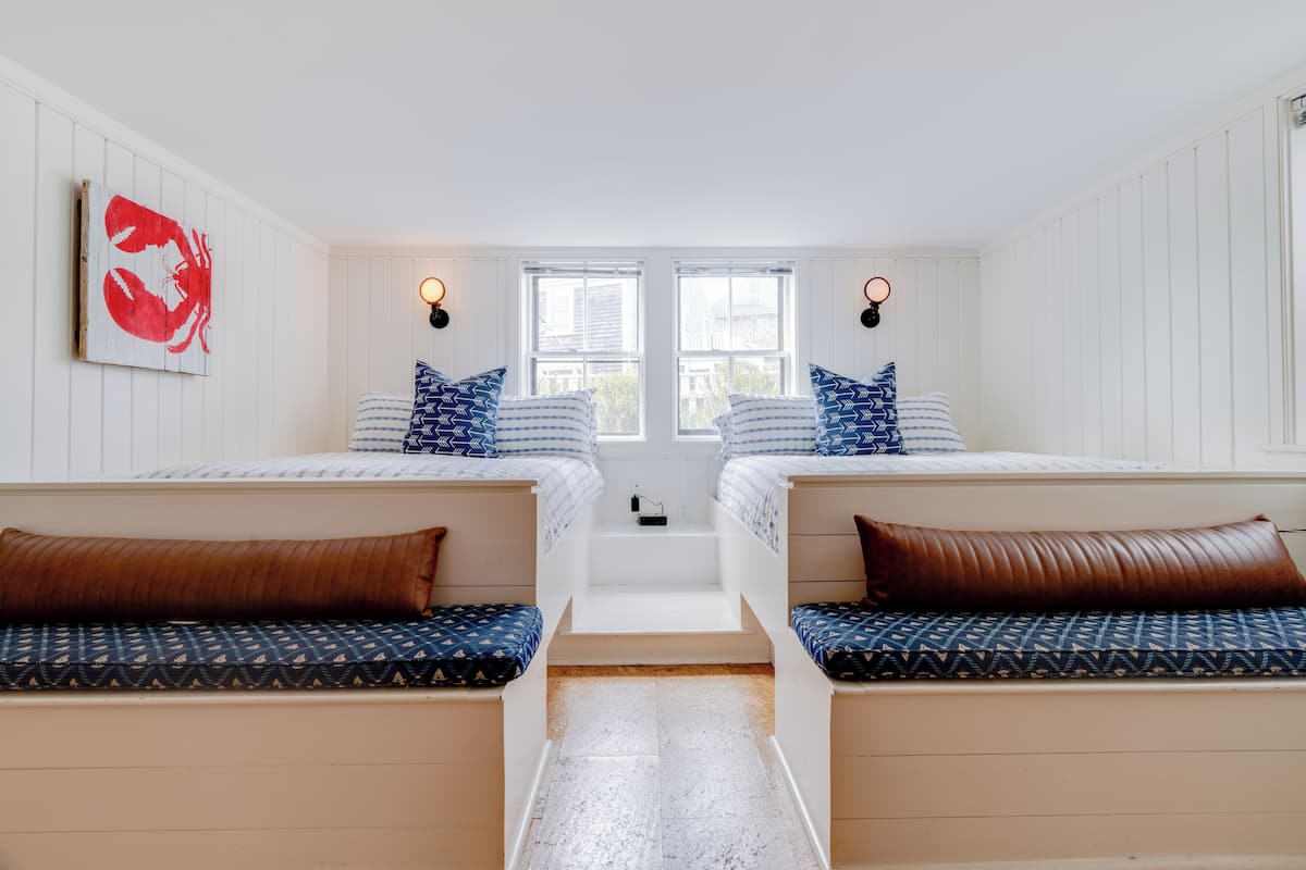 A room with two beds, a bench, and a staircase.