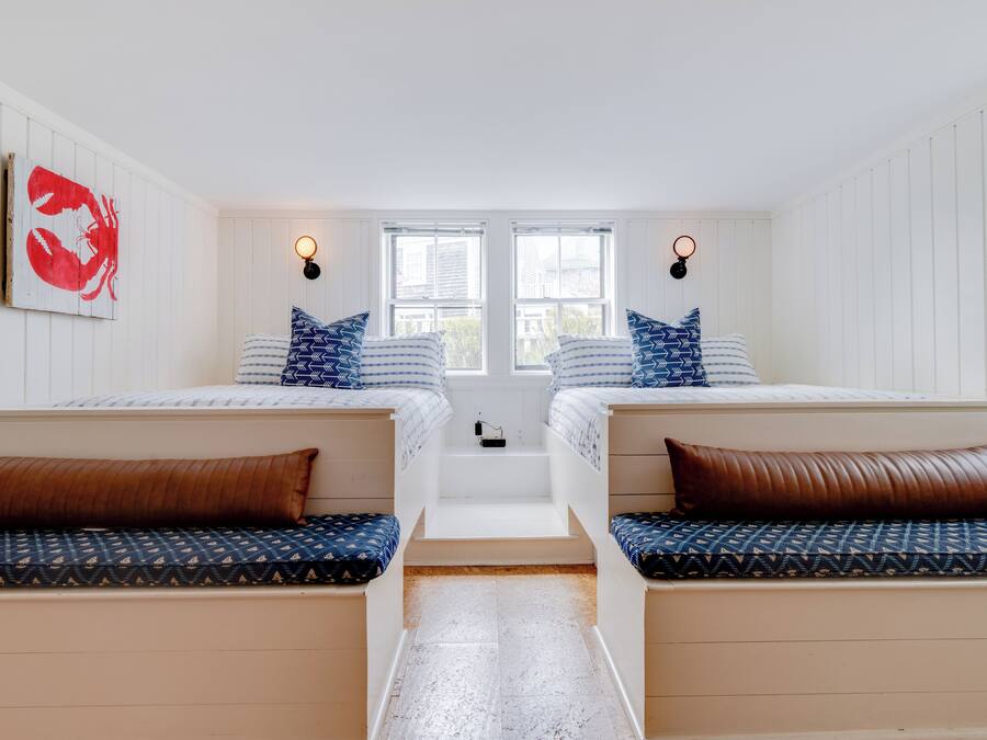 Una habitación con dos camas, un banco y una escalera.