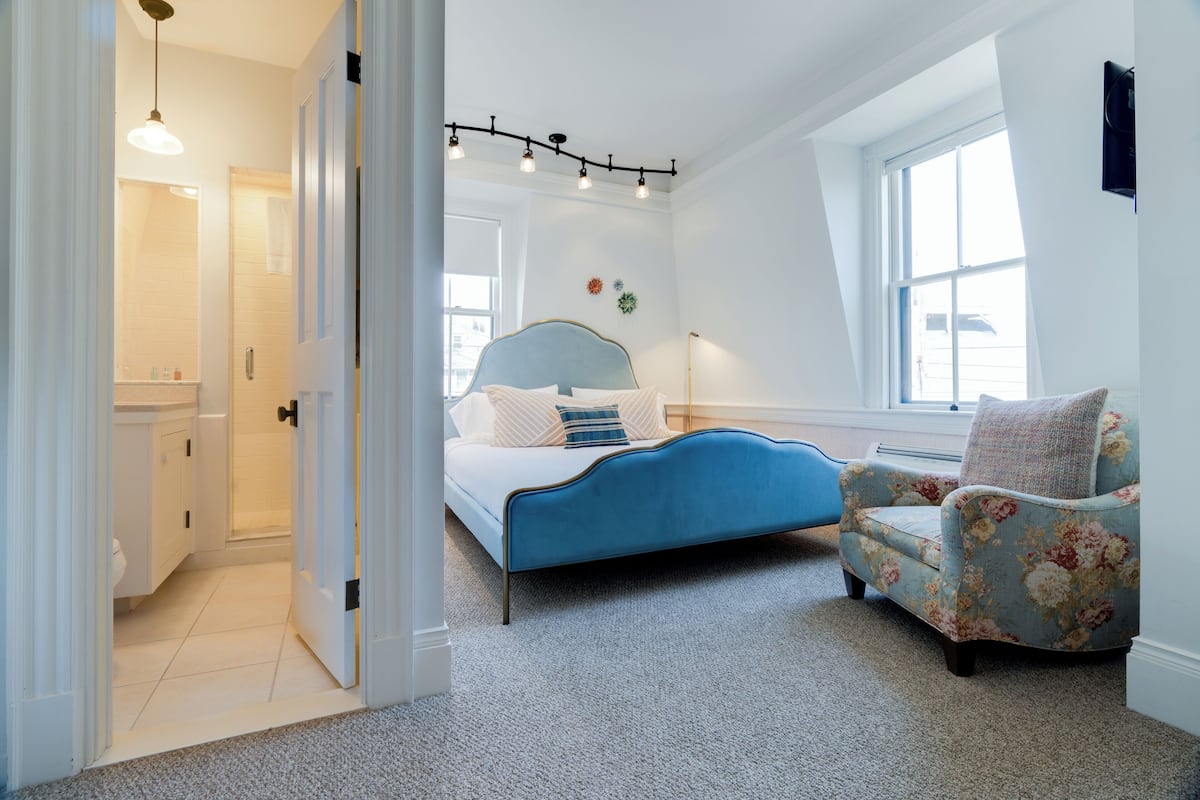 A bedroom with a bed, a chair, a window, and a door.