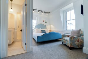 A bedroom with a bed, a chair, a window, and a door.