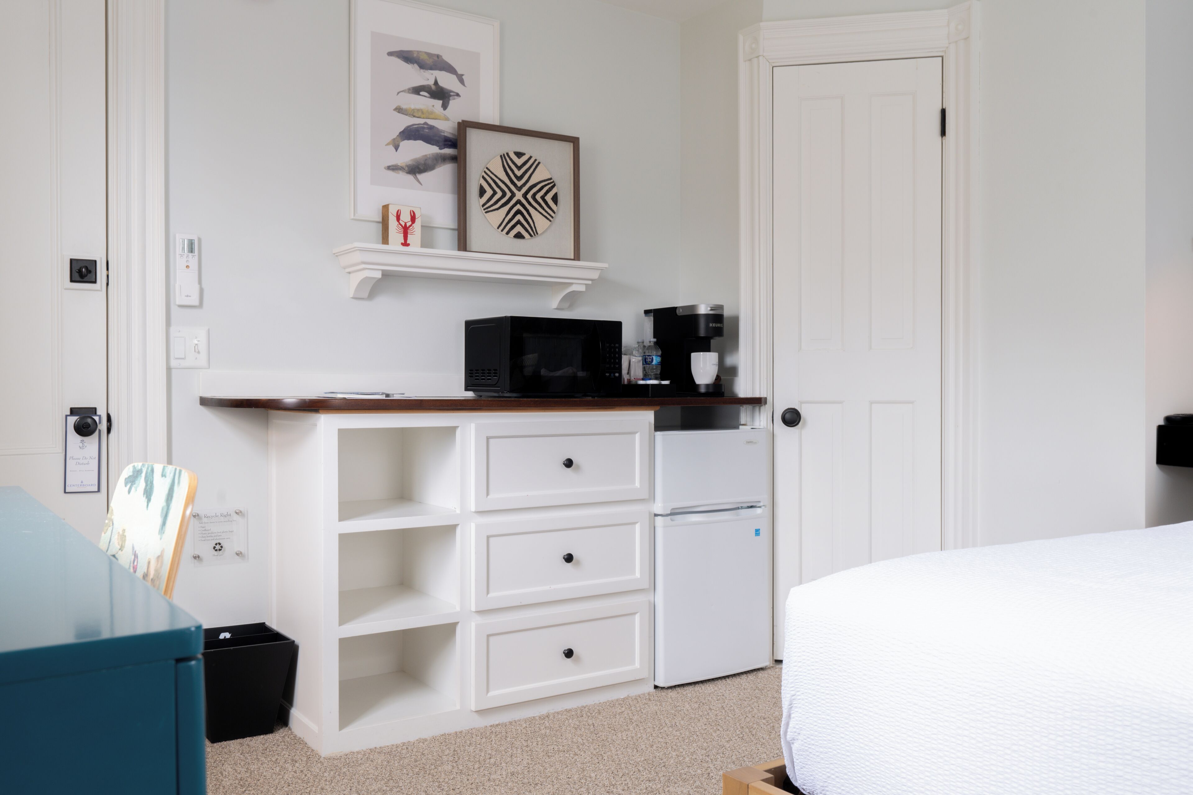 Un dormitorio con una cama, un escritorio con computadora, un microondas y un refrigerador.