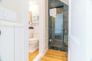 A bathroom with a toilet, a glass shower enclosure, and a white sink.