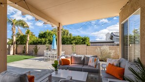 A covered patio with outdoor furniture, a blue umbrella, and a brick wall.