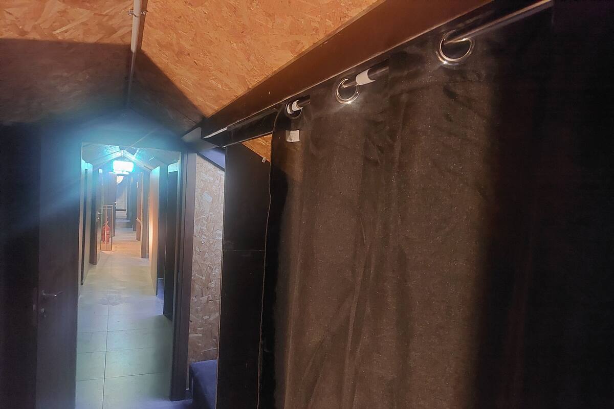 A narrow hallway with a wooden ceiling and a black curtain on the right.