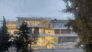 A modern building with multiple floors, large glass windows, and a construction site in the foreground. - malka hostel (Jerusalem)