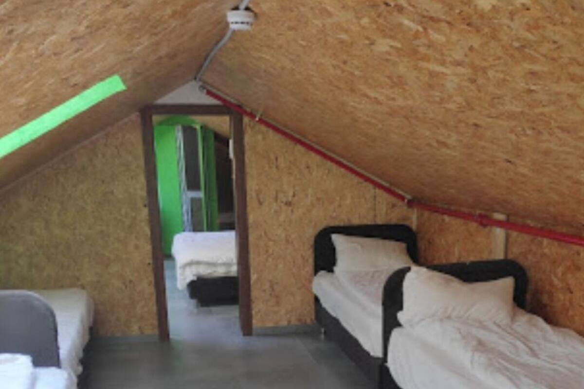 A dormitory room with two beds, a green door, and a tiled floor.