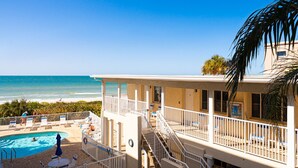 A beachfront hotel with a pool, a balcony with a railing, and a view of the ocean.