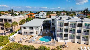 A hotel with a rooftop pool, multiple balconies, and a view of the surrounding neighborhood.