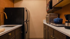 A modern kitchen with a black refrigerator, wooden cabinets, a stainless steel sink, and a unique ceiling light fixture. - Condo On The Beach - Heated Pool - Self Check-in (Belleair Beach)